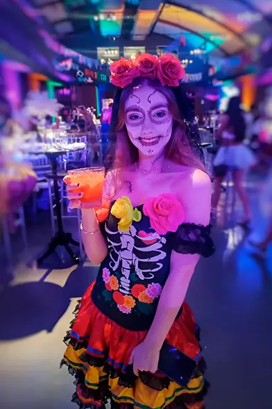 Convidada fantasiada com drink em evento temático